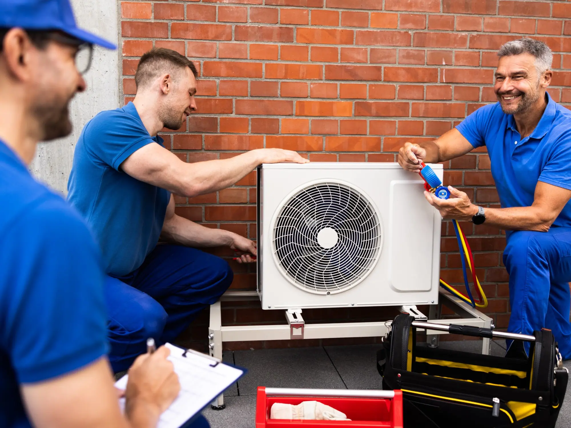 Technicians installing and testing air conditioning unit.