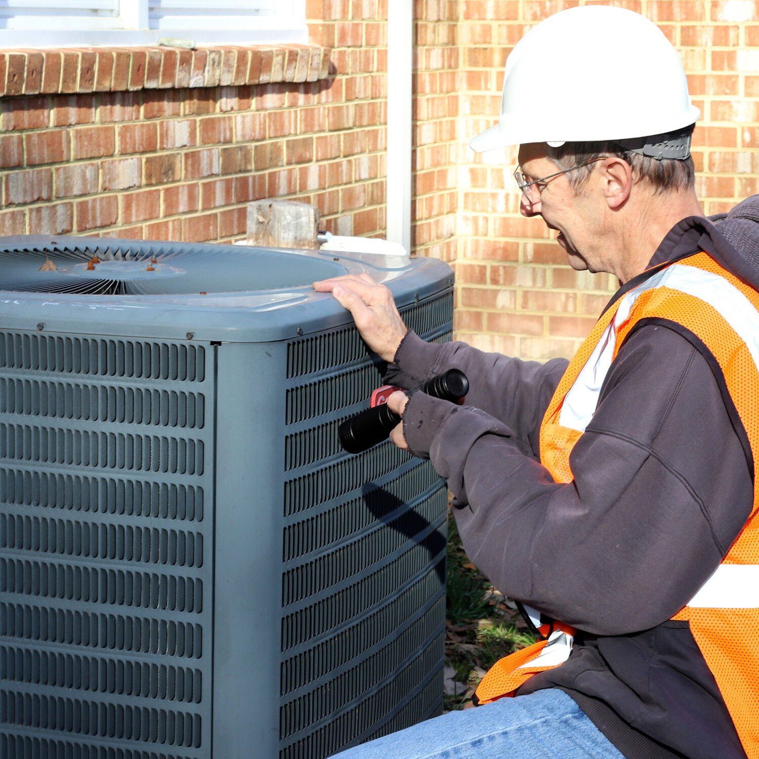 Technician inspecting outdoor air conditioning unit.