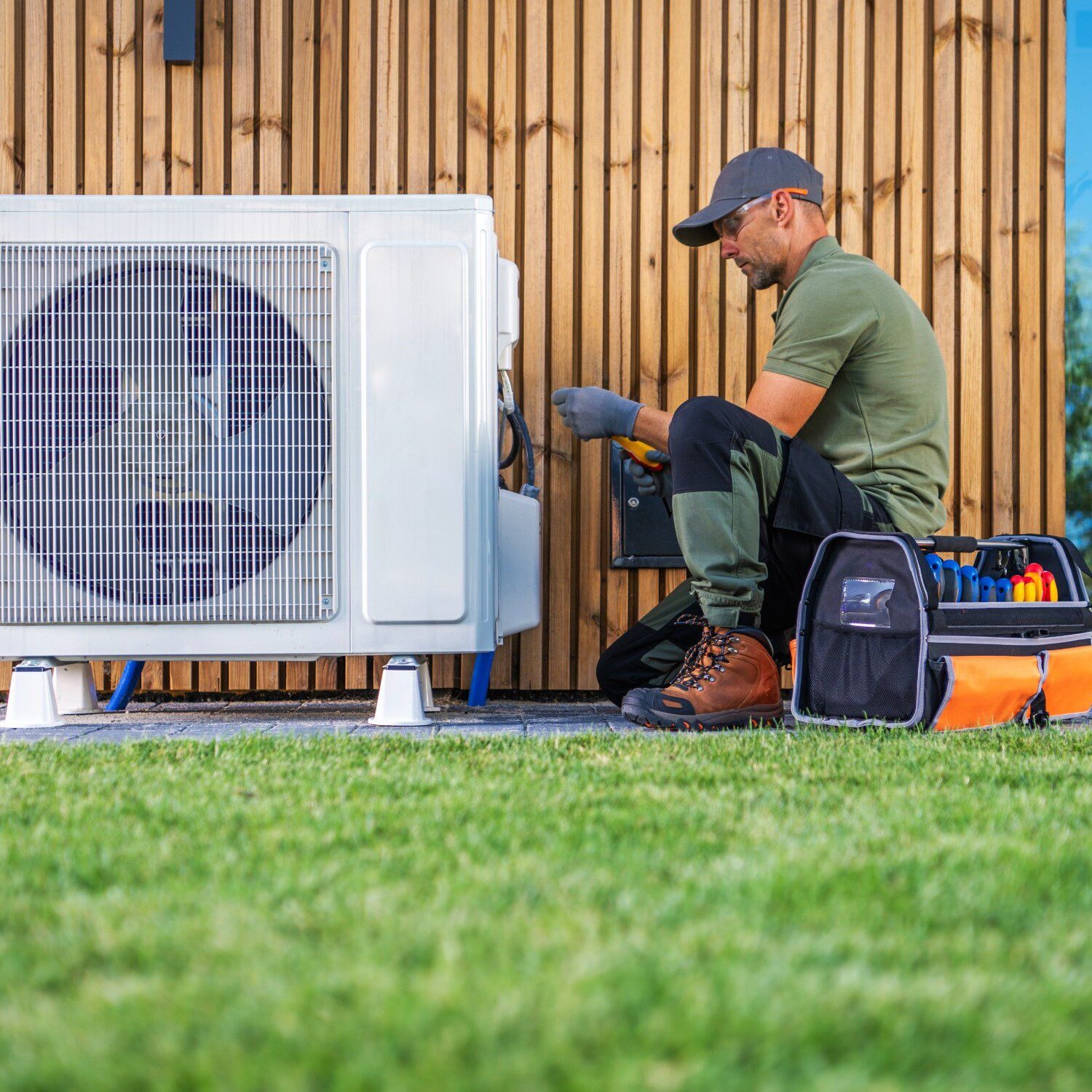 Technician repairing outdoor air conditioning unit.